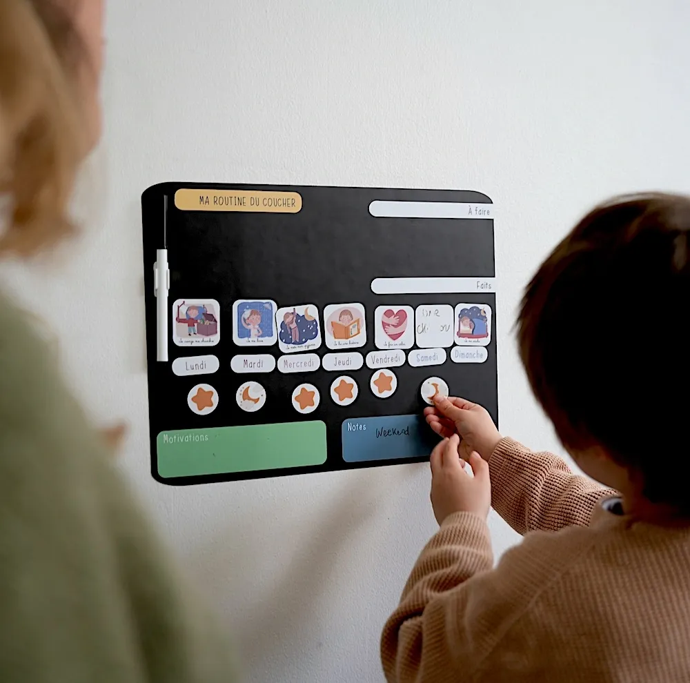 Enfant déplaçant un aimant sur un tableau de routine du coucher